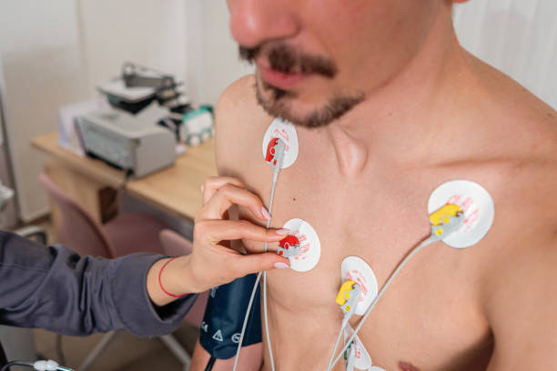 Close up of an female nurse adjusting electrodes on a male patient's chest, preparing him for the stress test on an exercise bicycle