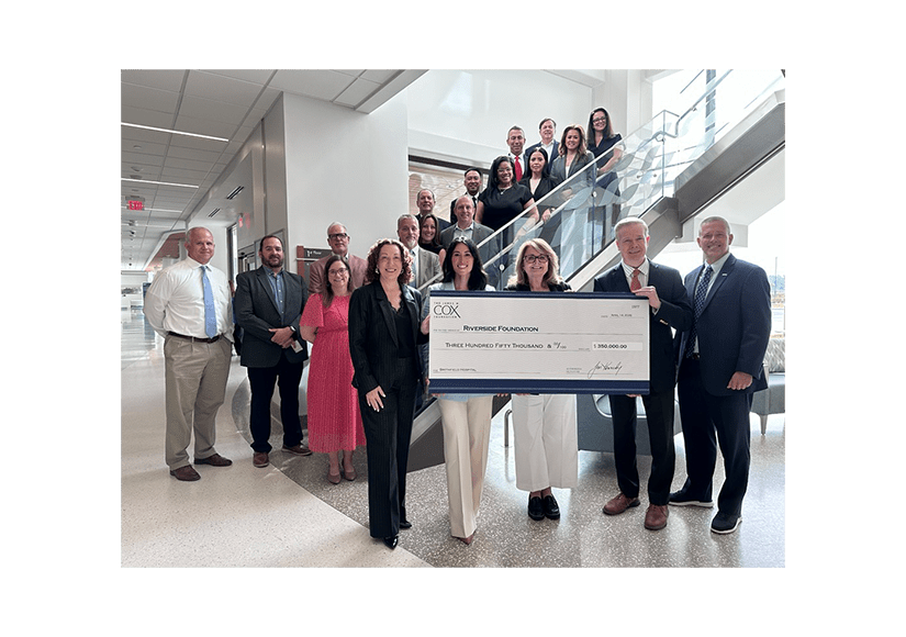 group of people standing on stairs smiling holding a check with 350,000 printed on it
