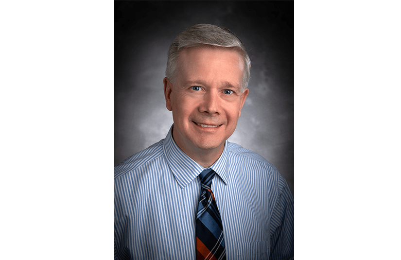 Caucasian man in a blue shirt and dark blue tie