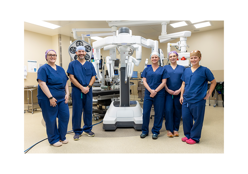 Group of medical professionals in surgical suite with robotic machine