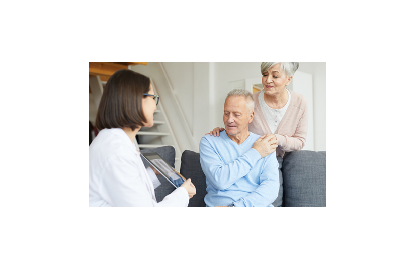 older man sitting with his wife with her hand on his shoulder