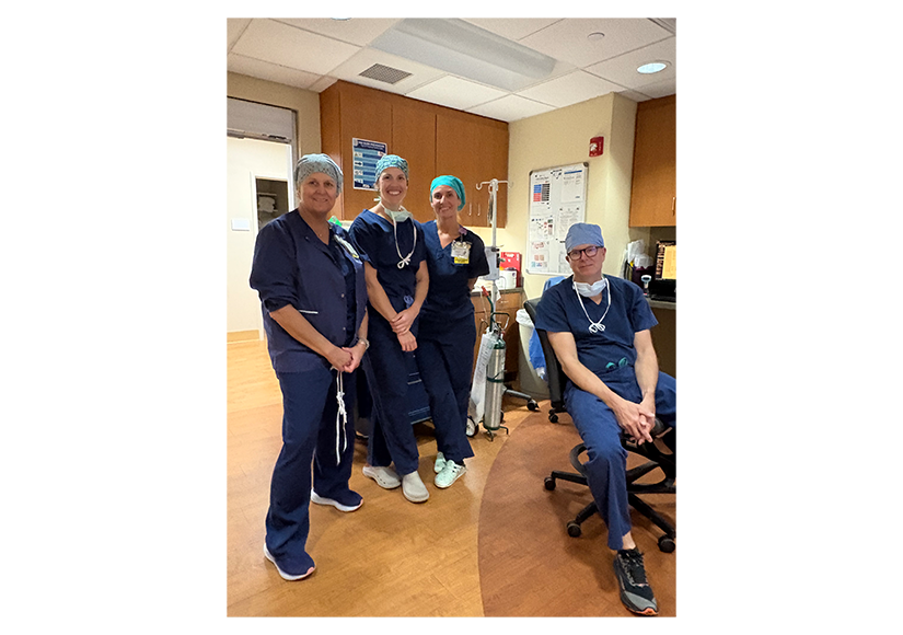 group of medical professionals in dark blue scrubs and light blue scrub caps
