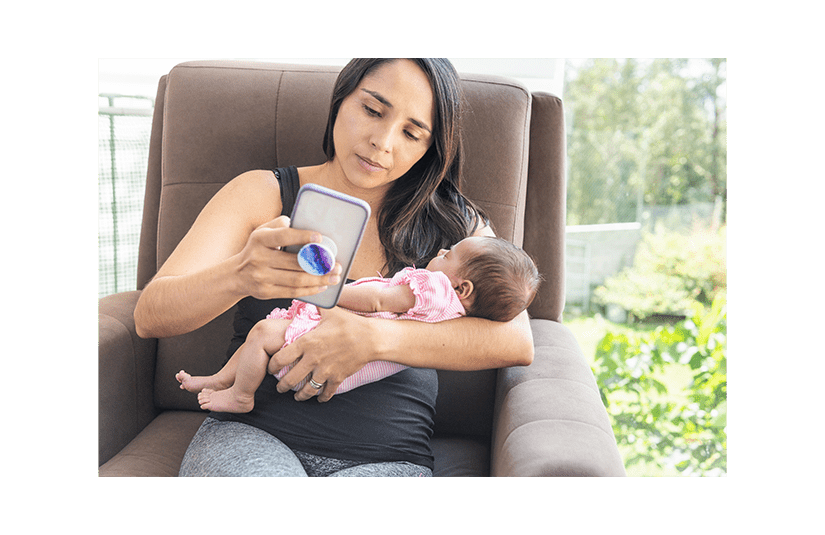 mother looking at her phone while holding her baby