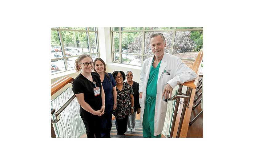 dr irvin smiling on a staircase surrounded by nurses