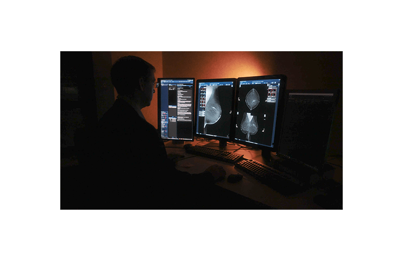 man sitting in front of computer looking at screening