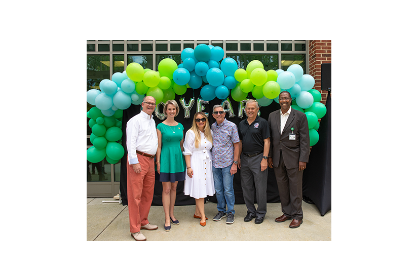 group of diverse individuals smiling in front of colorful balloons