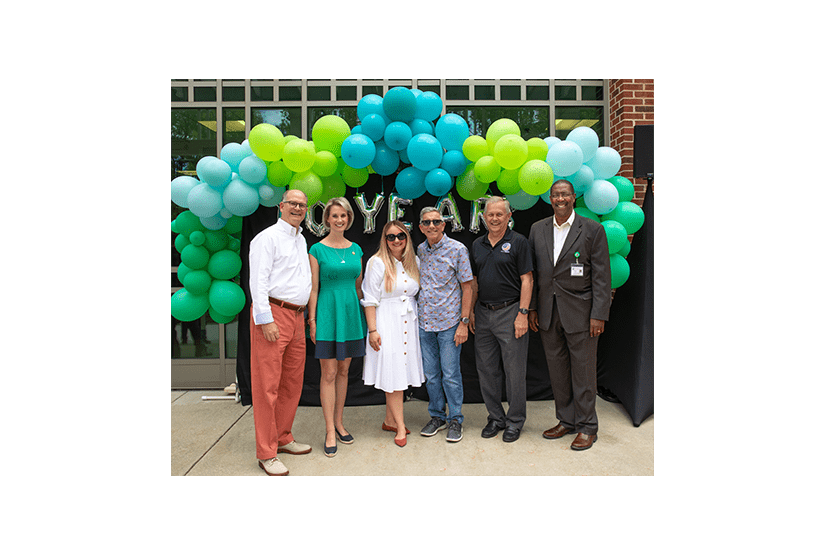 group of diverse individuals smiling in front of colorful balloons