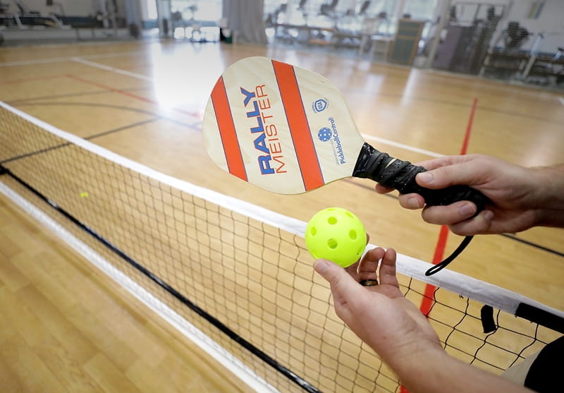 Person holding pickleball and racket