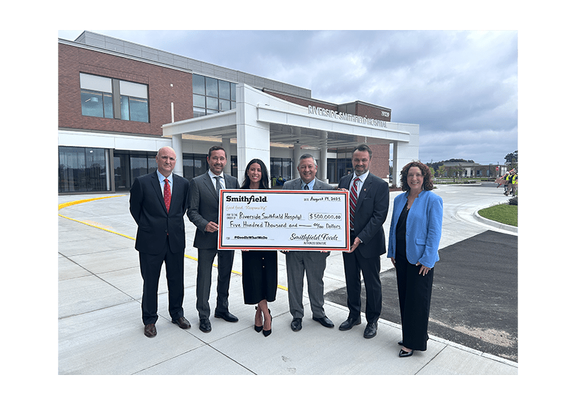 Group of people with a giant check in front of the hospital