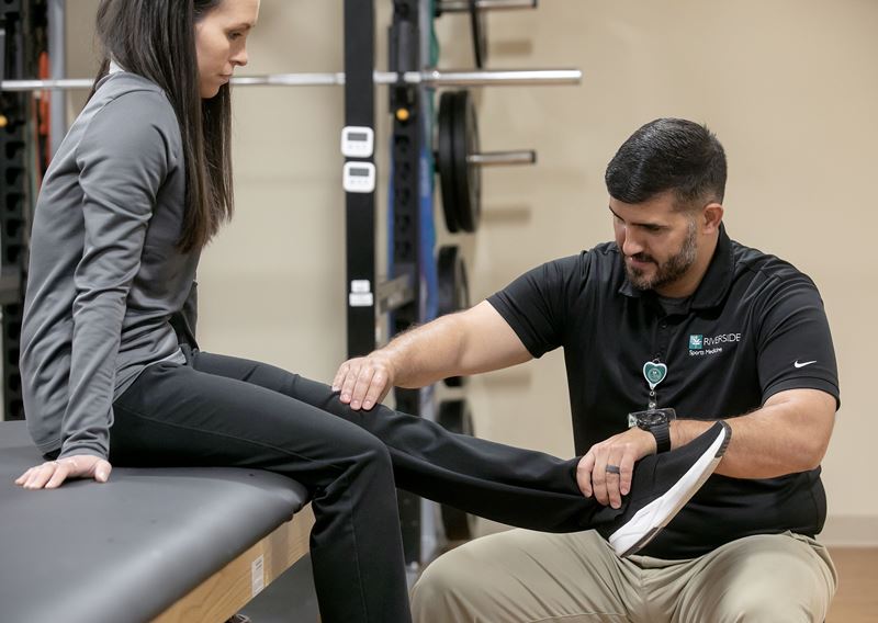 physical therapist examines a woman patient's leg in clinic
