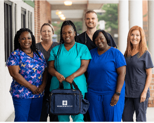 Diverse Riverside Health clinical team members standing together outside a medical facility, representing teamwork, inclusion and a culture of belonging in healthcare.