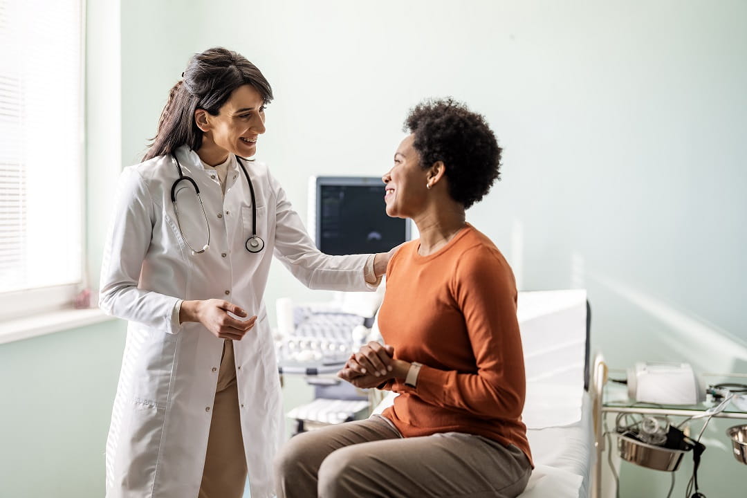 two women standing in a doctors office smiling