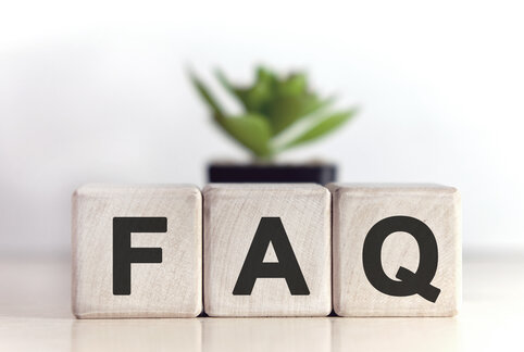 Have questions? FAQ concept on wooden cubes and flower in a pot in the background