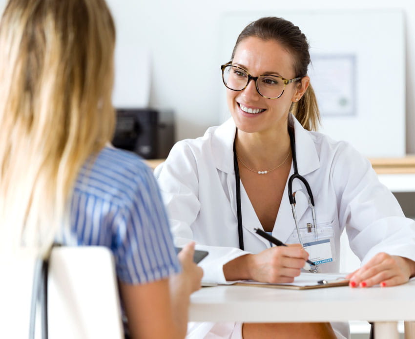 Woman in striped shirt receives health screening from female physician