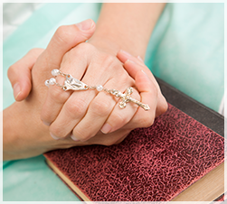 two hands holding a rosary over a book