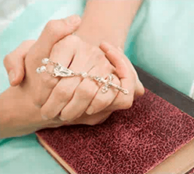 two hands holding a rosary over a book