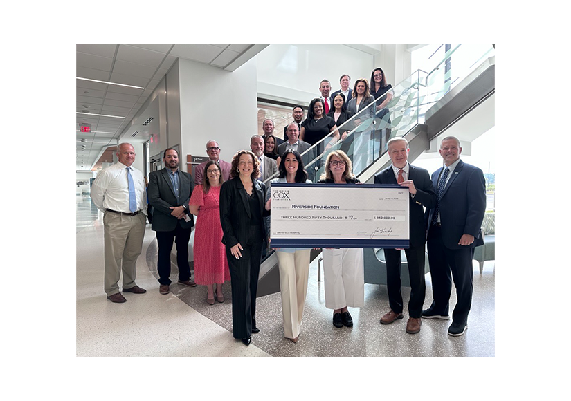 group of people standing on stairs smiling holding a check with 350,000 printed on it
