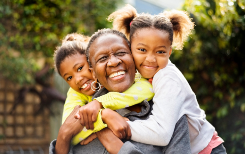 Senior woman cuddling her two granddaughters outdoors