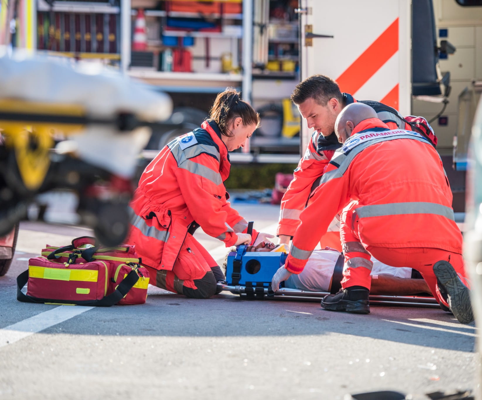 Paramedics providing first aid to man injured in car accident.