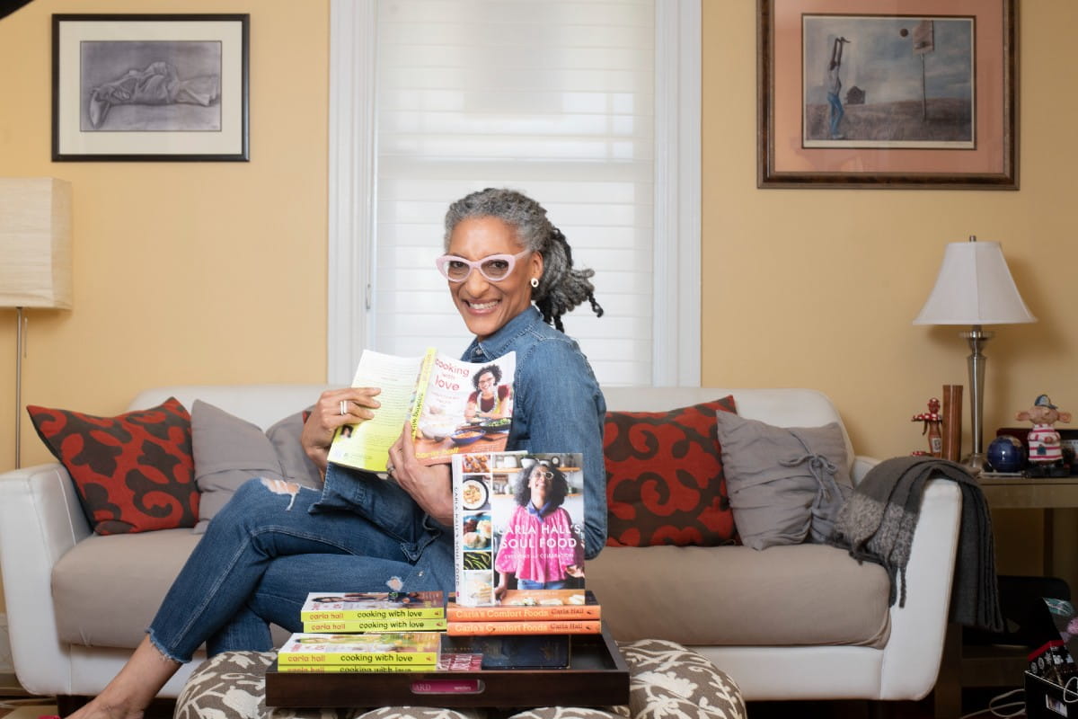 Black woman sitting on a couch with her books smiling