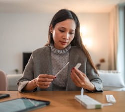 Asian American woman looking at a self covid test