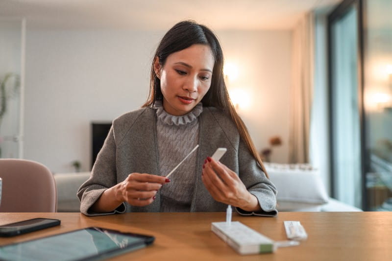 Asian American Woman looking at a at home covid self test