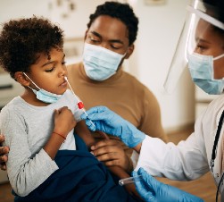 African American child getting tested for covid-19 with dad