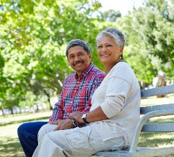 Older black couple sitting on a park bench