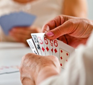 Focus on senior woman's hand holding cards during cards game.