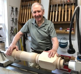 older white man standing in front of woodworking shop