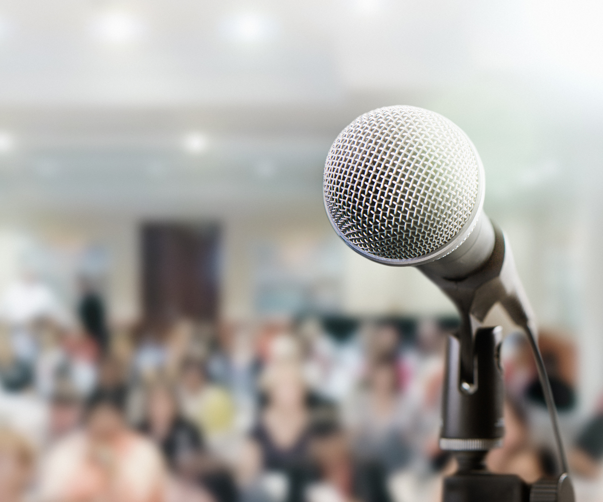 microphone in the foreground of the photo with a blurred crowd in the background