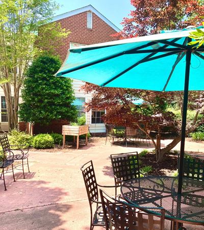 Evergreen courtyard with a blue umbrella and metal tables
