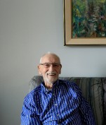 older man in a blue striped shirt sitting on a couch