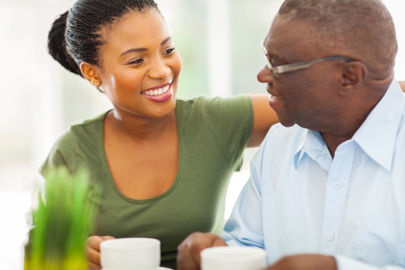 African american woman smiling at an older man in a blue button up shirt