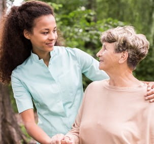 Older white woman in a peach shirt smiles at african american woman in a blue shirt