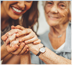 Woman clasping hand of elderly woman