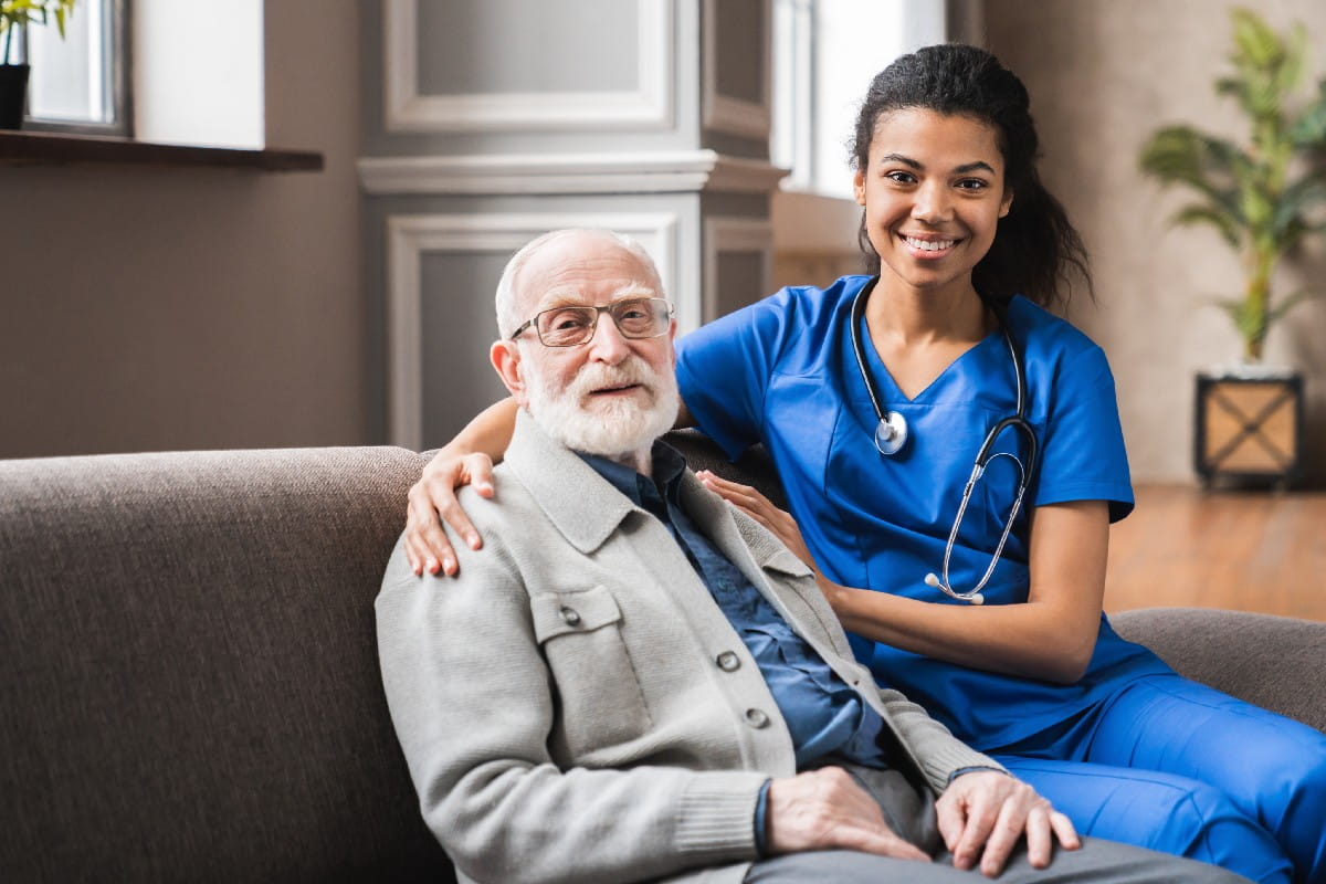 Healthcare professional seated beside an older adult in a comfortable residential setting, highlighting compassionate senior care, personalized support, aging in place services and trusted healthcare assistance.