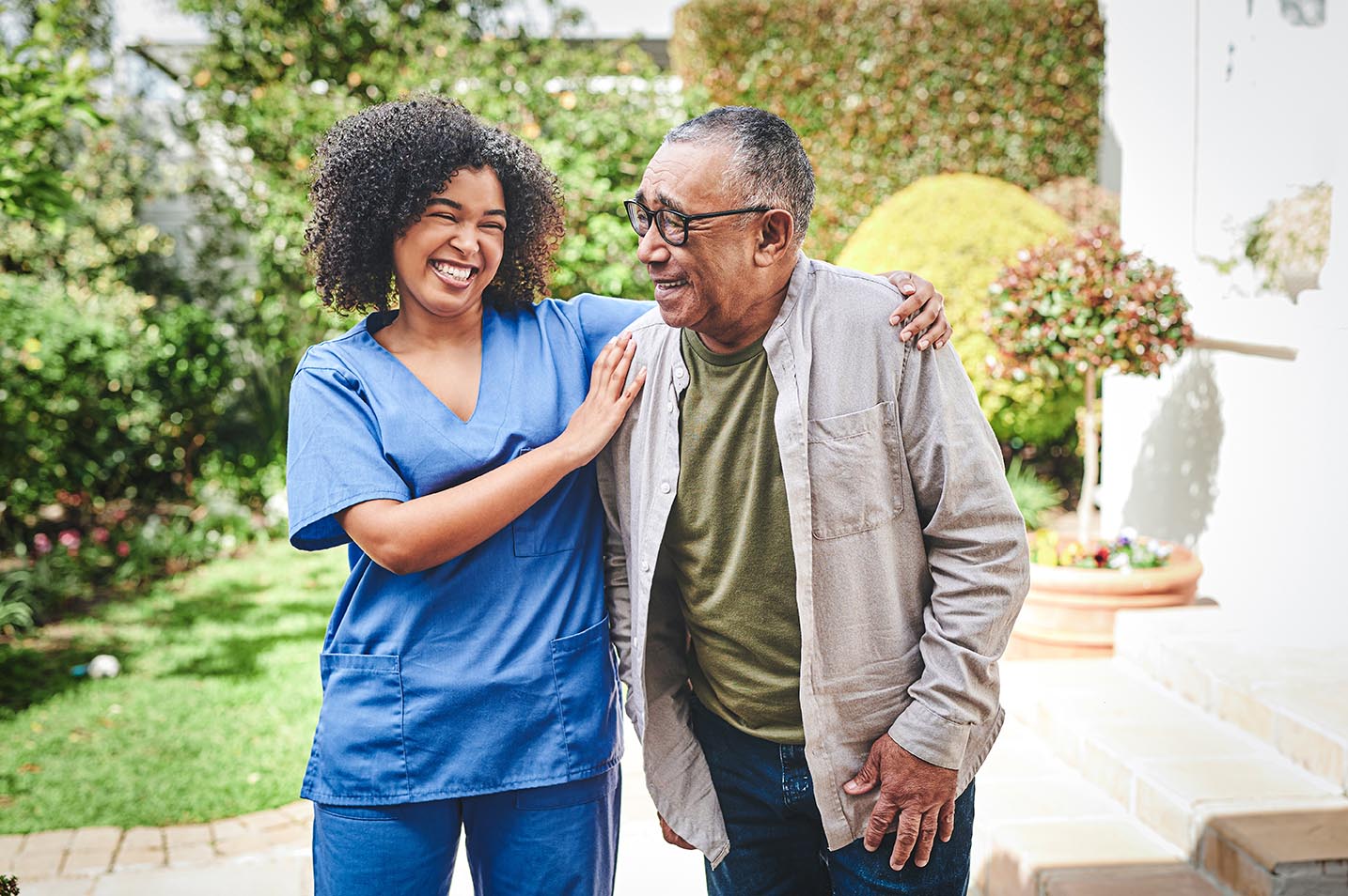 A female nurse laughing with an elderly man.