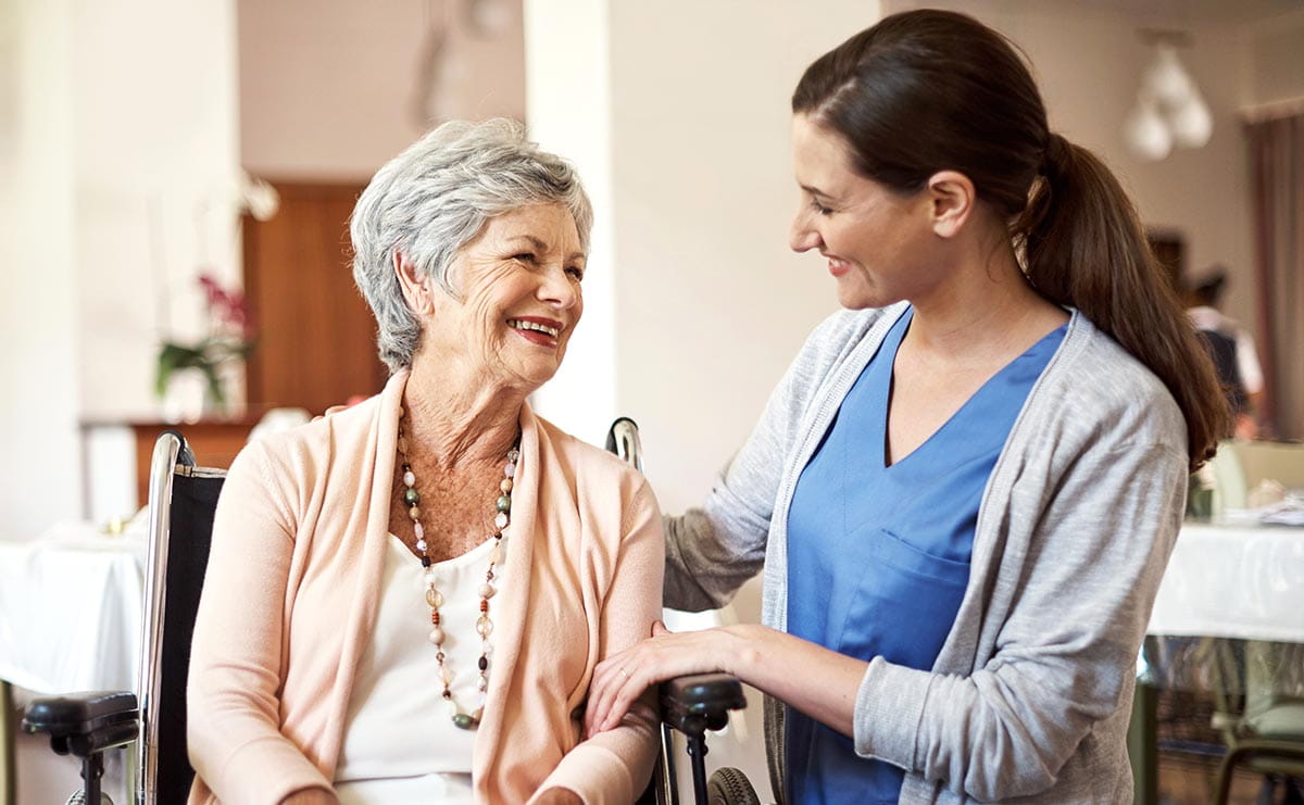 Young nurse caring for a senior woman in a home.