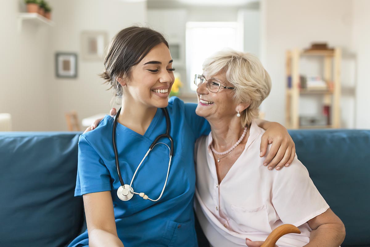 Home Health Services Young smiling nurse with her elderly happy patient.