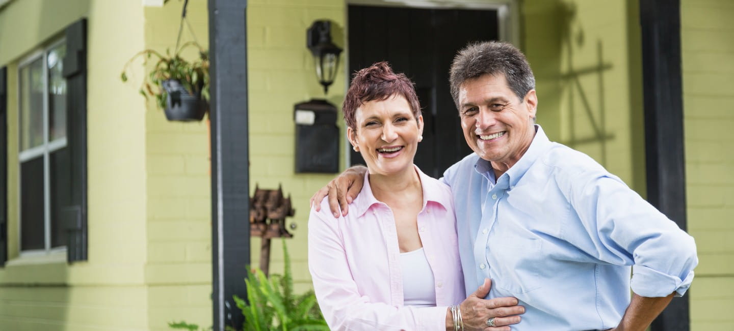 older hispanic woman smiling in a pink shirt hugging a man in a blue button up shirt