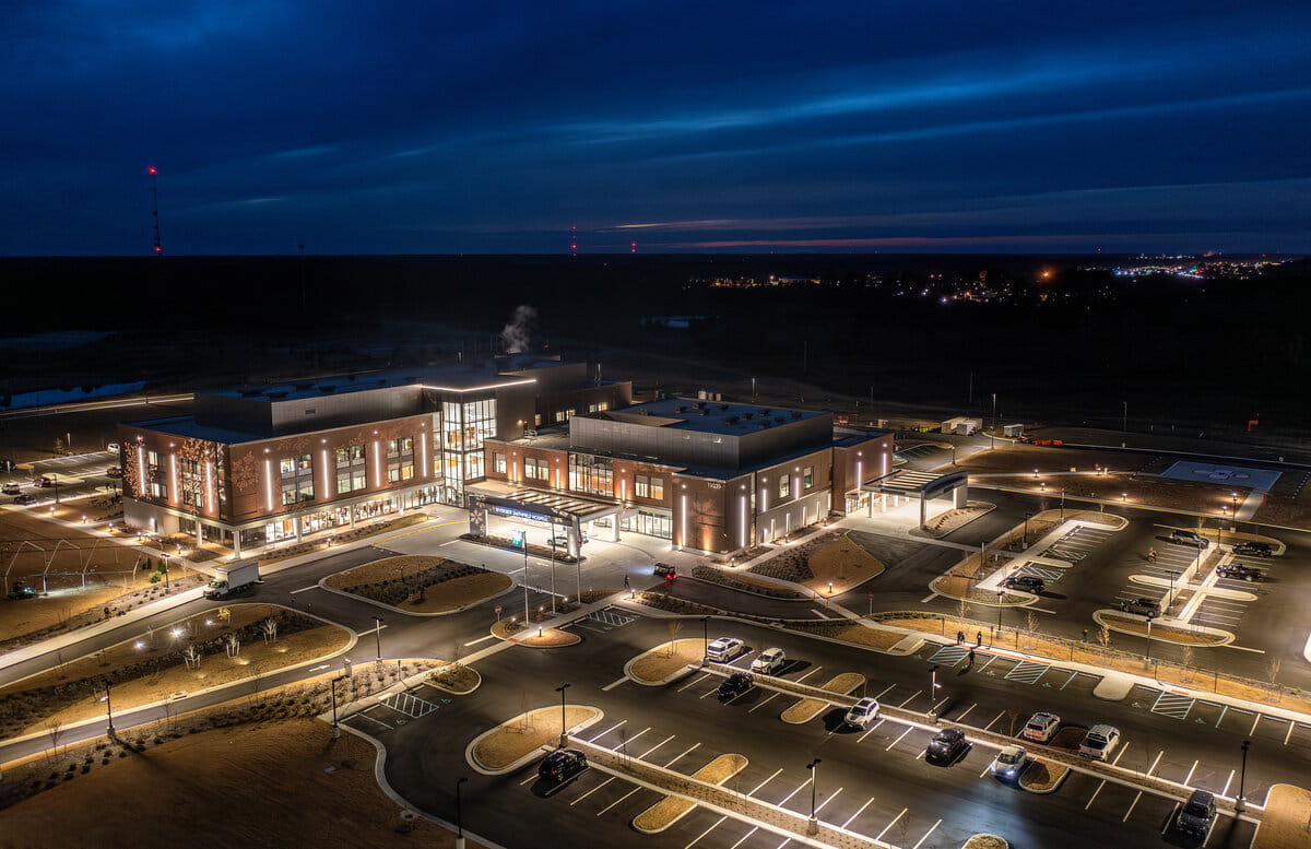 Aerial view of Riverside Smithfield Hospital and parking lot at night, set against a dark sky with a hint of orange. The scene conveys a calm, vibrant atmosphere.
