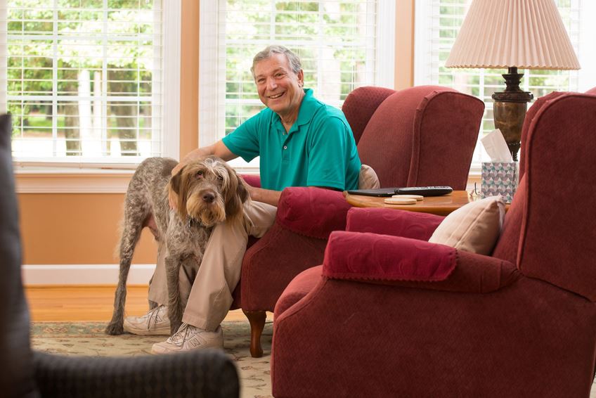 older adult in chair with a dog