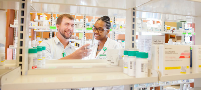 Two pharmacists choosing a drug from the shelves
