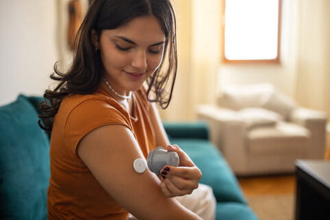Woman applying glucose sensor on arm