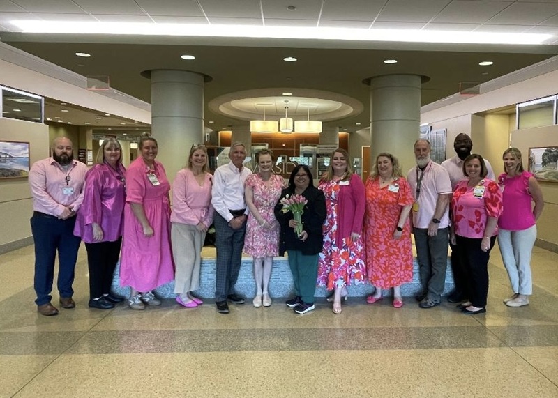 line of people dressed in varying shades of pink standing in a line smiling 