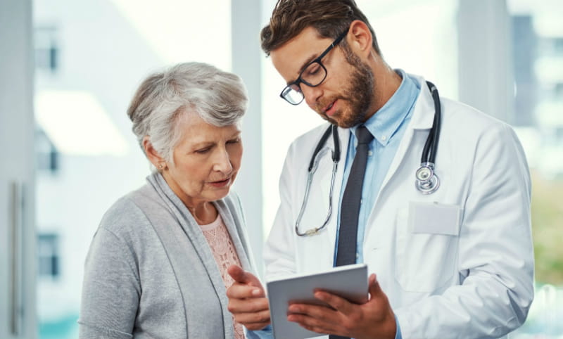 Doctor and older woman look at tablet
