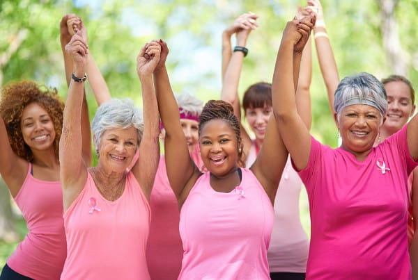 group of diverse women wearing pink holding hands