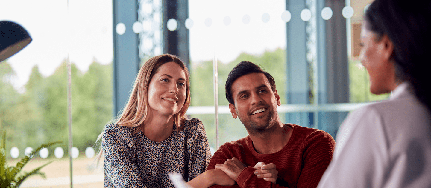 Woman Doctor Discussing Test Results With Smiling Couple in Hospital