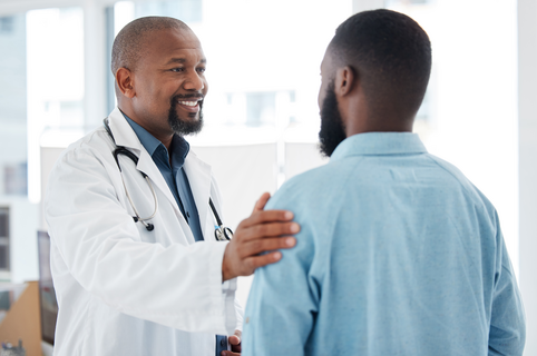 Personalized attention you can feel Mature doctor giving a patient support. African american doctor touching a patient on the arm. Patient in a consult with his doctor. Caring doctor giving a patient comfort and support.